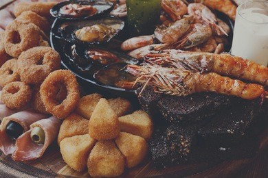 seafood platter. mediterranean cuisine restaurant food closeup, fried calamari rings, king prawns, mussels, oysters, shellfish delicacy on wood table background. catering, banquet table