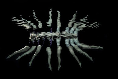 synchronized swimmers take a pose underwater