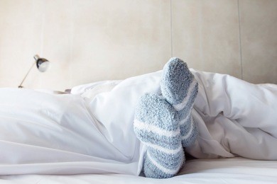 female foot in warm stripe wool sock ,woman sleeping and relaxing in bed concept, rare view