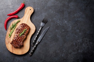 grilled beef steak on cutting board over stone table. top view with copy space