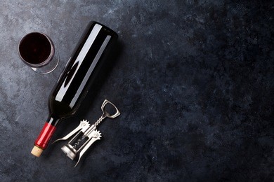 red wine glass and bottle on stone background. top view with copy space