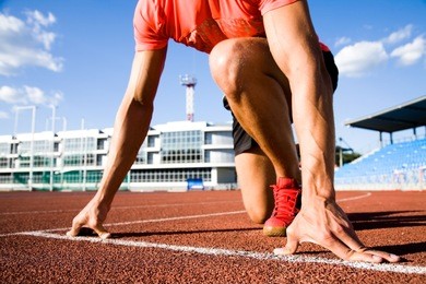 young muscular athlete is at the start of the treadmill at the stadium