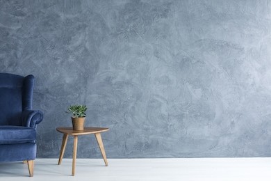interior with grey wall blue armchair and wood side table