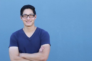 portrait of a handsome asian man with glasses crossing his arms