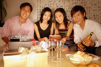 couples sitting down, looking at camera, cake in front of them