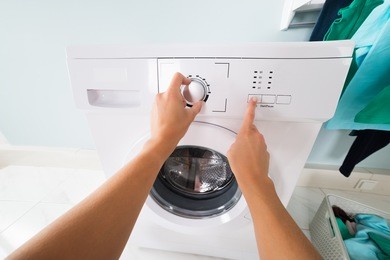 pov view of woman pressing button of washing machine at laundry room