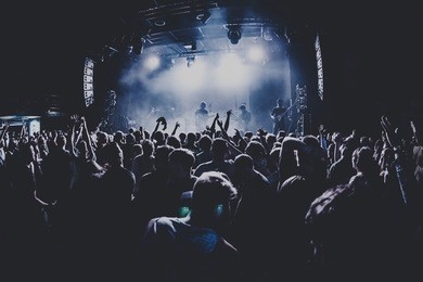silhouettes of concert crowd in front of bright stage lights. dark background, smoke, concert  spotlights