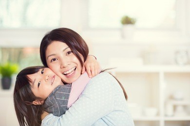 portrait of happy japanese mother hugging with her cute little daughter at home