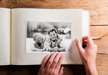hand holding photo album with pictures of senior couple. studio