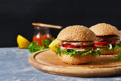 big homemade burger with meat, tomato and sauce on a cutting board. concrete background. fast food.