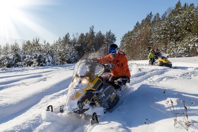 the sportsman on a snowmobile moving through deep snowdrifts in the winter forest in the mountains of the southern urals.