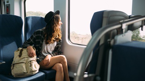 beautiful girl in hat with a backpack sitting in the train. traveling, journey.
