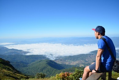 the blue shirt man who traveling alone, sitting and enjoying the view at kew mae pan nature trail on doi inthanon national park, thailand