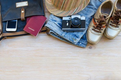 essential travel accessories: backpack, hipster sneakers and vintage camera on wooden background.  top view. copy space. traveling concept.