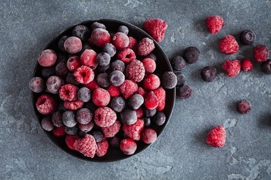 frozen raspberry, blueberry, cranberry on black background. frozen fruit. top view, flat lay, close up.
