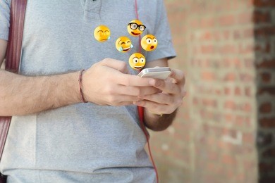 close-up of man using smartphone sending emojis. social concept.