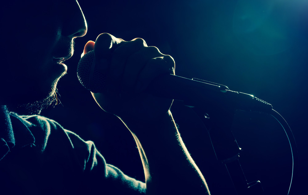 closeup songer hand holding the microphone and singing on black