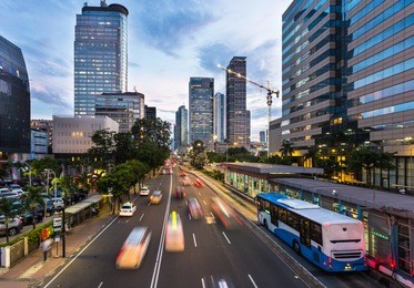 traffic rushes in jakarta business district along the city main avenue jalan thamrin at sunset in indonesia capital city. the transjakarta bus system enjoys its own traffic lane to avoid congestion.