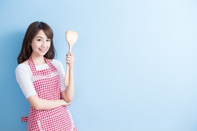 beauty housewife take rice spoon and smile isolated on blue background