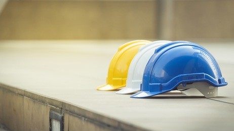 white, yellow and blue hard safety helmet hat for safety project of workman as engineer or worker, on concrete floor on city