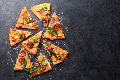 homemade pizza with tomatoes, mozzarella and basil. top view with copy space on dark stone table 