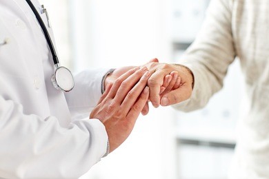 medicine, age, support, healthcare and people concept - close up of doctor or nurse holding senior man hand at hospital