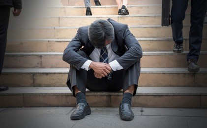 depressed businessman bending down the head sitting on the stairs. unemployed middle edge man feel frustrated after business failure.