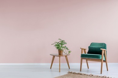 pink room with green armchair, rug and side table