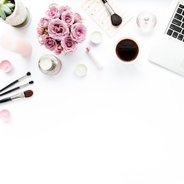 office table desk. laptop, computer. magazines, social media. top view. flat lay. home office workspace. women's fashion. bouquet of roses, notebook, coffee on white background. makeup tools brushes 