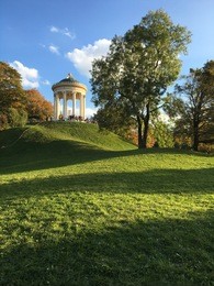 long autumn shadows as sun sets over the lush green hills of the english garden in munich.