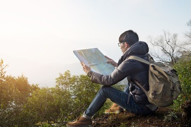young man traveler with map backpack relaxing outdoor with rocky mountains on background summer vacations and lifestyle hiking concept.