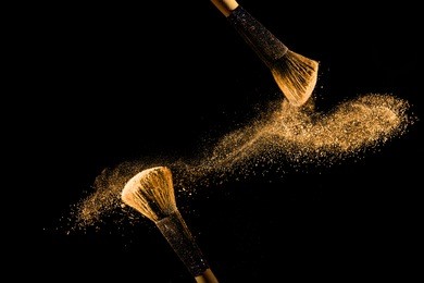cosmetic brush with golden cosmetic powder spreading on black background