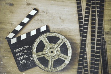 clapperboards and the reel of film lie on a wooden board.
