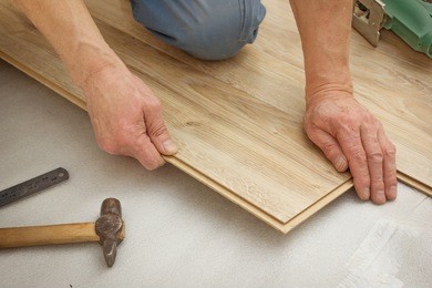 man makes laying laminated panels, simulating light oak