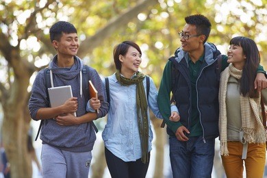 four happy asian college students walking together in the campus