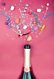 colorful party attributes fly out from botle of champagne wine. on a red background. flat lie. celebrate concept. high resolution photo.