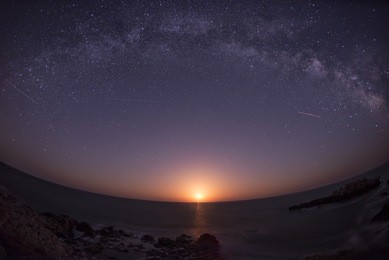 moon rising under the milky way galaxy