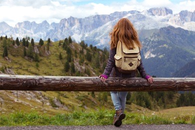 girl hiker sitting  and looking at the snowed mountains. dolomites, italy.
