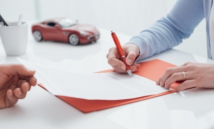 woman signing a car insurance policy, the agent is holding the document