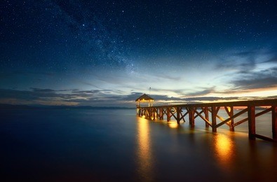 beautiful night seascape with stars in the sky and pier stretching into the ocean. summer, travel, vacation and holiday concept - wooden pier between sunset in north sulawesi, indonesia.