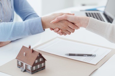 real estate broker and customer shaking hands after signing a contract: real estate, home loan and insurance concept