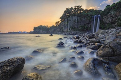 view of famous jeongbang waterfall and motion sea on jeju island of south korea.