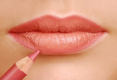 red lipstick cosmetic pencil. make-up tool. woman lips close up