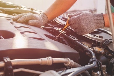 hand of technician checking or fixing engine of modern car