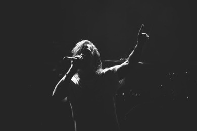 frontman silhouette singing to the microphone to the crowd on a concert in a stage backlights. black and white.