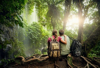 couple travelers with backpacks relaxing in greens jungle and enjoying view in waterfall. island lombok, indonesia.
traveling along mountains and rain forest, freedom and active lifestyle concept
