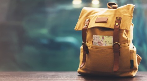 hipster yellow backpack and map closeup. view from front tourist traveler bag on background blue sea aquarium. person hiker visiting ocean museum in barcelona on backdrop, blank blurred mock up