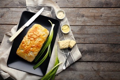 plate with tasty loaf of beer bread on wooden background