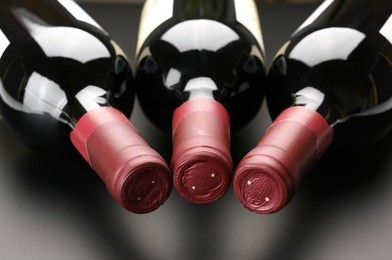 three closed red wine bottles lying on dark background.