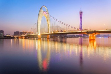 light show in sunset time at modern bridge in zhujiang river and modern building of financial district in guangzhou city, china